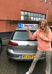 Geslaagde leerling in roze hoodie wijst naar het lesbord